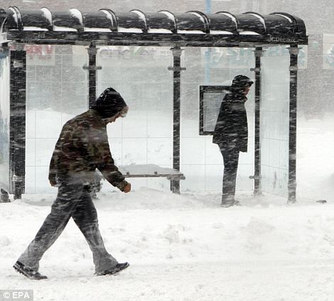 A man waits for a Chicago Transit Authority bus (R) while another decides to walk through a snowstorm on the south side of Chicago, Illinois