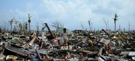A survivor walks among the debris of houses destroyed by Super Typhoon Haiyan in Tacloban on the eastern Philippine island of Leyte on November 11, 2013. (photo: AFP/Noel Celis)