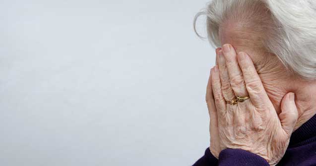 Elderly woman covers face