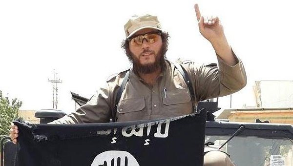 ISIS jihadist with ISIS flag and one-finger ISIS salute