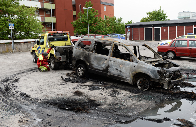A burned-out van is prepared for removal after youths rioted in Husby, northern Stockholm on May 21, 2013 (AFP Photo / Jonathan Nackstrand)