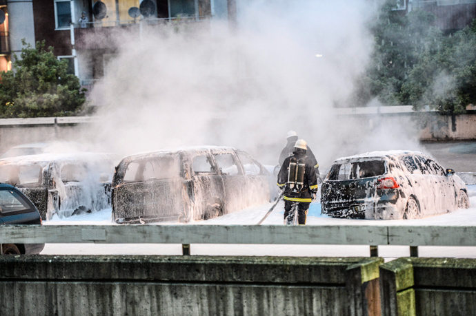 Policemen extinguish burning cars after youths rioted in Husby, northern Stockholm on May 20, 2013 (AFP Photo / Fredrik Sandberg / Scanpix Sweden/ Sweden out)